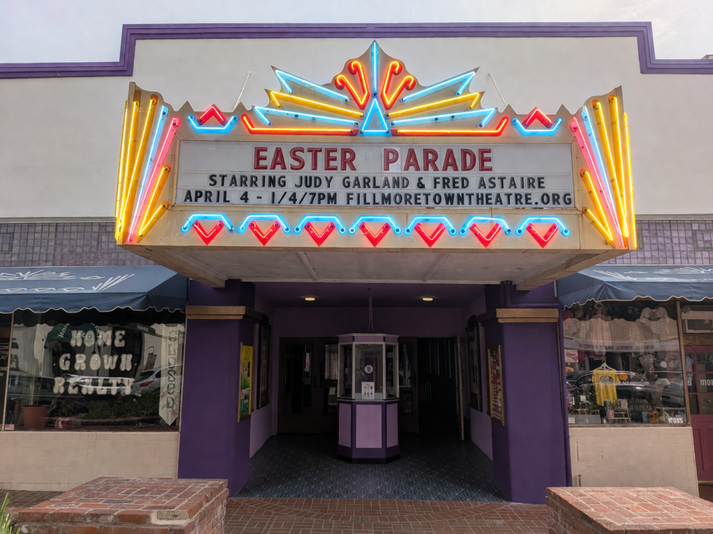 Front view of the Fillmore Town Theatre entrance with vintage marquee reading “Easter Parade” starring Judy Garland and Fred Astaire, with showtime listed for April 4 at 7 PM.