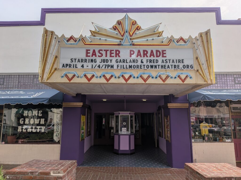 Front view of the Fillmore Town Theatre entrance with vintage marquee reading “Easter Parade” starring Judy Garland and Fred Astaire, with showtime listed for April 4 at 7 PM.